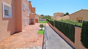 Una strada residenziale con case, un vialetto lastricato e un siepe curata.