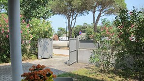 An outdoor seating area with a table and chairs, surrounded by greenery and a gated entrance. - Veronica by Interhome (Lido di Volano)