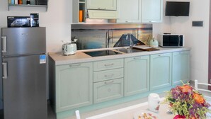 A kitchen with light green cabinets, a stainless steel refrigerator, a toaster, a sink, and a microwave. - Veronica by Interhome (Lido di Volano)