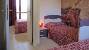 Une chambre d’hôtel avec deux lits, une table de chevet, une lampe et un grand tableau abstrait accroché au mur.