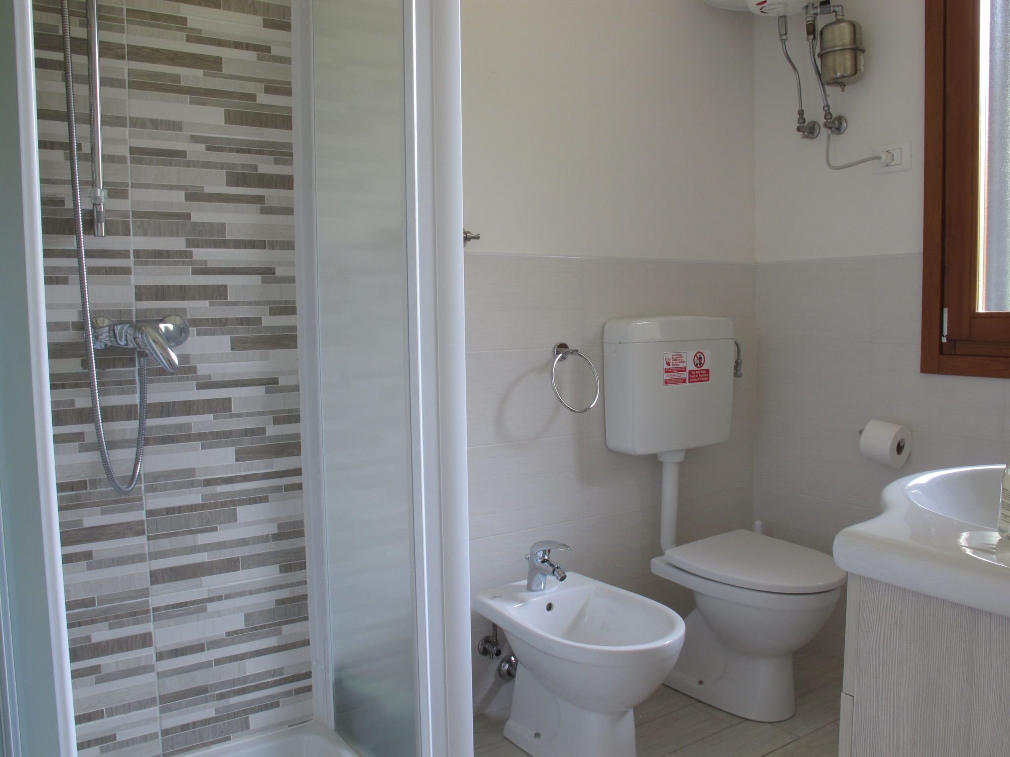 Ein Badezimmer mit Dusche, Toilette, Bidet und Waschbecken.