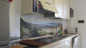 Une cuisine avec une fresque murale représentant une plage, un four à micro-ondes et un évier.