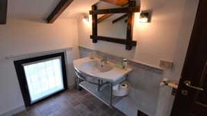 Une salle de bain avec un lavabo blanc, un miroir et une fenêtre.