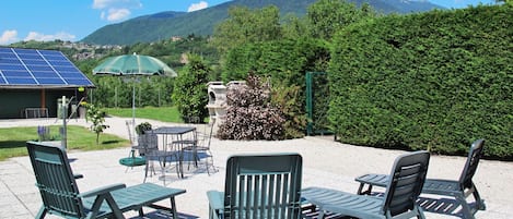 An outdoor seating area with chairs and tables, solar panels, and a view of mountains.