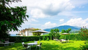 A well-maintained garden with outdoor seating, a view of a mountain, and a building in the background. - Villetta ai Pini by Interhome (Lago di Caldonazzo)