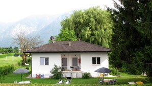 A white house with a tiled roof, a balcony, and a fenced yard with outdoor furniture. - Villetta ai Pini by Interhome (Lago di Caldonazzo)