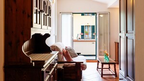 Uma sala de estar aconchegante com um piano, um sofá e uma mesa de jantar. Há uma janela grande com vista para o exterior.