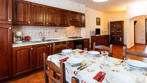 A kitchen with wooden cabinets, a dining table set for four, and a modern light fixture. - La Colombera by Interhome (Diano Marina)