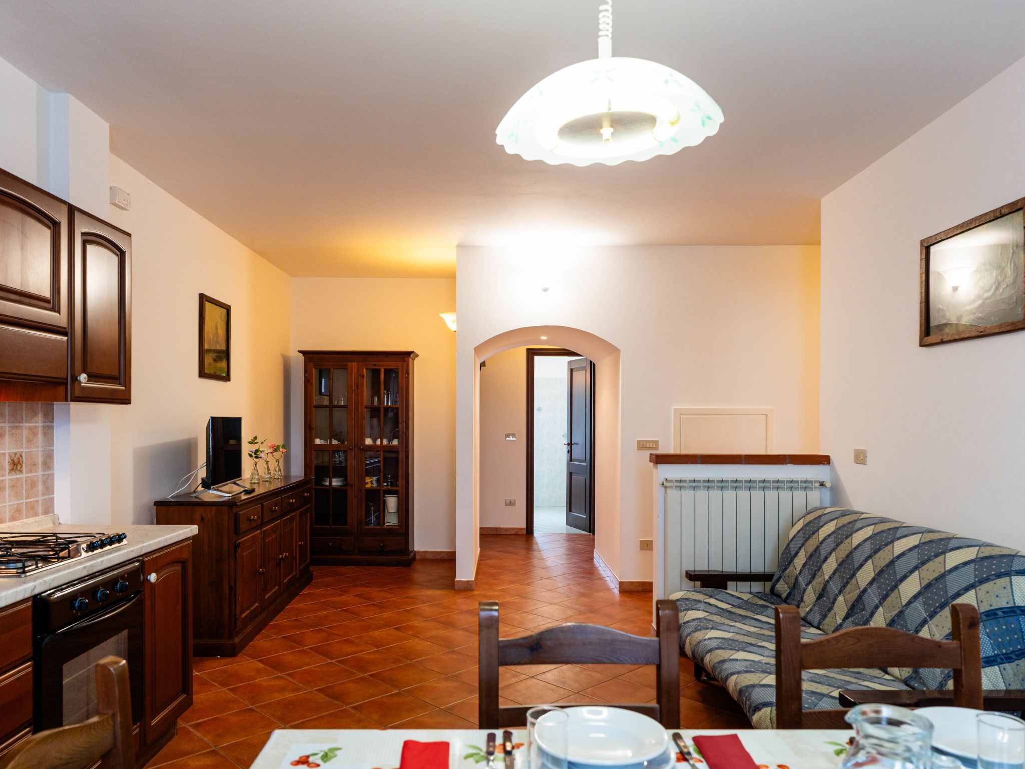 A kitchen with a stove, cabinets, and a dining area with a table set for two.