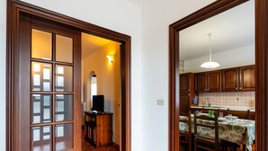 Eine Küche mit Holzausstattung, einem Esstisch mit Tischdecke und einem Fernseher im Hintergrund.