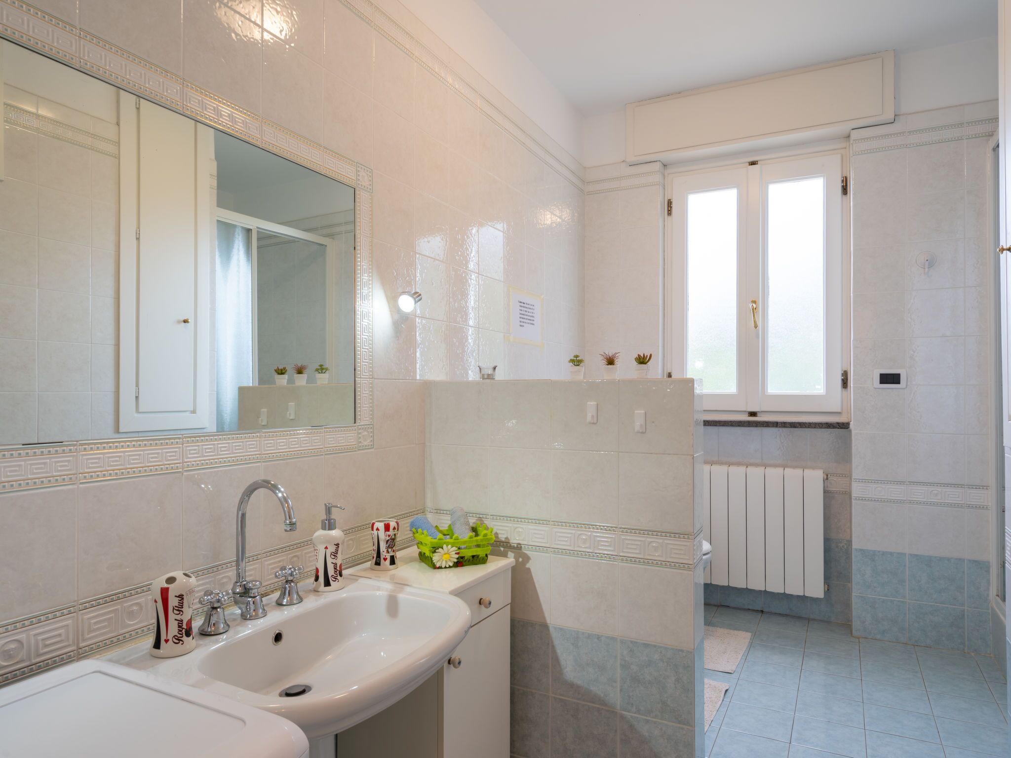 A bathroom with a sink, mirror, and a window.