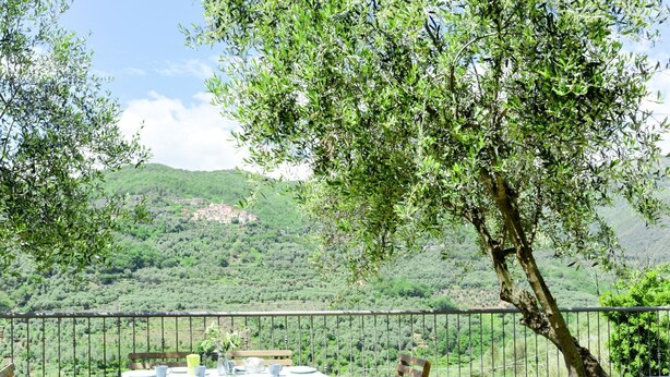 A table set outdoors with a view of a hillside village. - Marco (PRE172) by Interhome (Molini di Prelà)