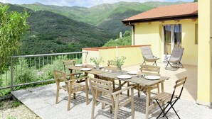 A wooden table and chairs set on a balcony with a mountain view. - Luca (PRE171) by Interhome (Molini di Prelà)
