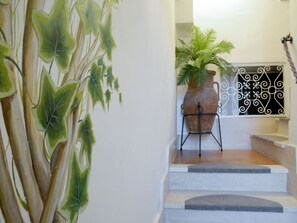 A staircase with a potted plant and a decorative metal gate. - Daniela (DOL295) by Interhome (Dolcedo)