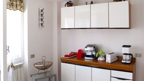 Eine Küche mit weißen Schränken, einer Kaffeemaschine, einem Toaster und einem Fruchtsaftpressen auf der Arbeitsfläche.