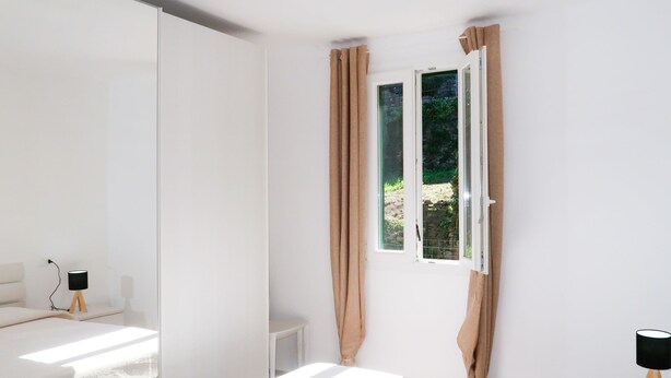 A modern bedroom with a large bed, a bedside table with a lamp, and a window with curtains. - A Ca' Gialla (AEG100) by Interhome (Albenga)