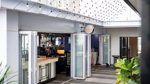 Un hall d’hôtel moderne avec une cloison en verre, un comptoir d’accueil et un panneau indiquant l’emplacement d’un restaurant.