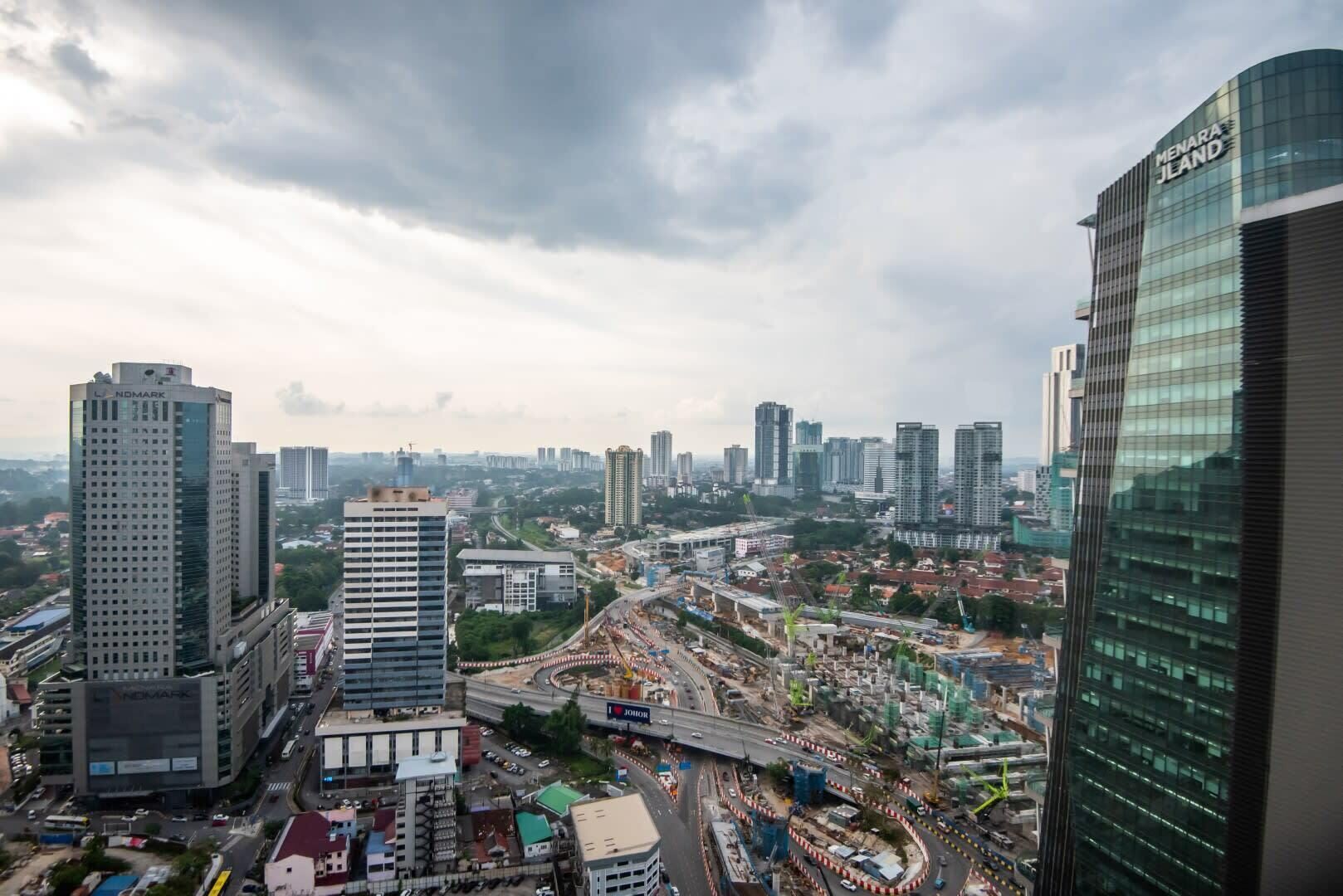 Panorama urbano con moderni grattacieli, tra cui spiccano gli edifici 'Menara JLand' e 'NOMARK'.