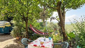 An outdoor garden with a table set for dining, surrounded by greenery and a hammock. - Elisa (DOL127) by Interhome (Dolcedo)