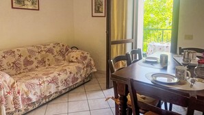 A dining area with a table set for two, a sofa, and two framed pictures on the wall. - Elisa (DOL127) by Interhome (Dolcedo)