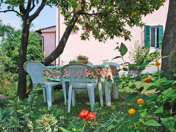 A garden with a table and chairs, surrounded by plants and flowers. - Elisa (DOL127) by Interhome (Dolcedo)
