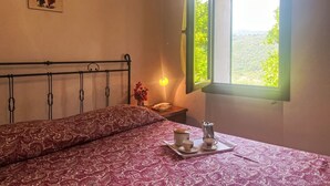 A bedroom with a bed, a nightstand, a window with a view, and a painting on the wall. - Elisa (DOL127) by Interhome (Dolcedo)