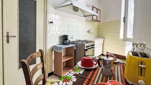 Une cuisine compacte équipée d’une cuisinière à gaz, d’une machine à café et d’un grille-pain jaune.
