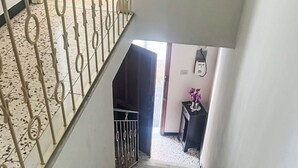 Un escalier avec une rampe métallique menant à une porte ouverte.