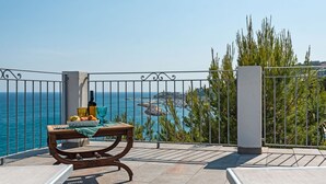 A balcony with a view of the sea, a table with fruits and a bottle, and a metal railing. - Ciliegi (SLR354) by Interhome (San Lorenzo al Mare)