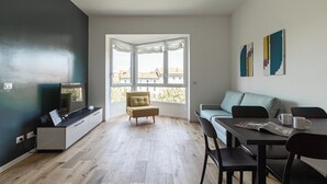 A modern living room with a sofa, a dining table, and a TV. - Italianway Comfort - D'aragona 2 (Milan)