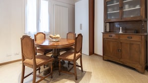 Un coin repas comprenant une table ronde en bois, six chaises rembourrées et un buffet aux portes vitrées.