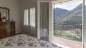 Une chambre avec un lit, une commode et un balcon offrant une vue sur la montagne.