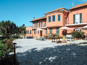 Un patio con suelo empedrado, mobiliario exterior y un edificio con varios balcones y ventanas.