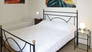 A bedroom with a single bed, a bedside table with a lamp, a nightstand, and a painting on the wall. - Arco (SLR350) by Interhome (San Lorenzo al Mare)