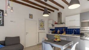 Een moderne keuken met een eethoek, met een grijze bank, een tafel met stoelen en een hanglamp.