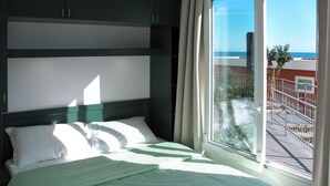 A hotel room with a bed, a window with a view of the sea, and a balcony with a railing. - Gelsomino (SLR403) by Interhome (San Lorenzo al Mare)