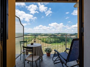 Un balcon avec une table, des chaises et un pot de fleurs.