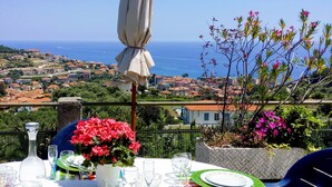 A table set for dining with a view of the sea and town in the background.