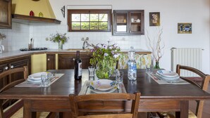 Mesa de comedor lista para cuatro personas, con una botella de vino, copas y platos.