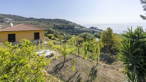 Una villa amarilla con techo de tejas que domina un paisaje costero.