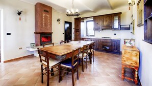 A spacious kitchen with a large wooden table and chairs, a built-in oven, and wooden cabinets. - San Giacomo by Interhome (San Damiano d'Asti)
