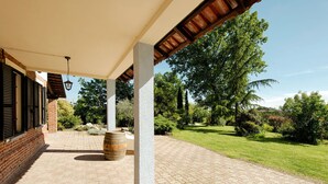 A covered patio area with a brick floor, a wooden barrel, and a pergola structure. - San Giacomo by Interhome (San Damiano d'Asti)