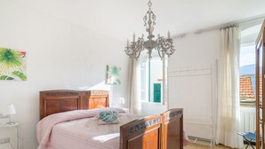 Une chambre à coucher avec un lit en bois, un lustre, une fenêtre avec des rideaux et une vue sur l’extérieur.
