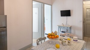 Un coin repas avec une table mise pour le petit-déjeuner, un saladier de fruits, une carafe et une cafetière.