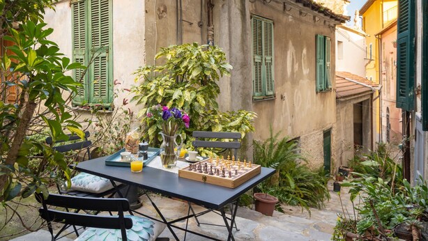 Une cour intérieure avec une table dressée pour le petit-déjeuner, entourée de verdure et de bâtiments historiques.