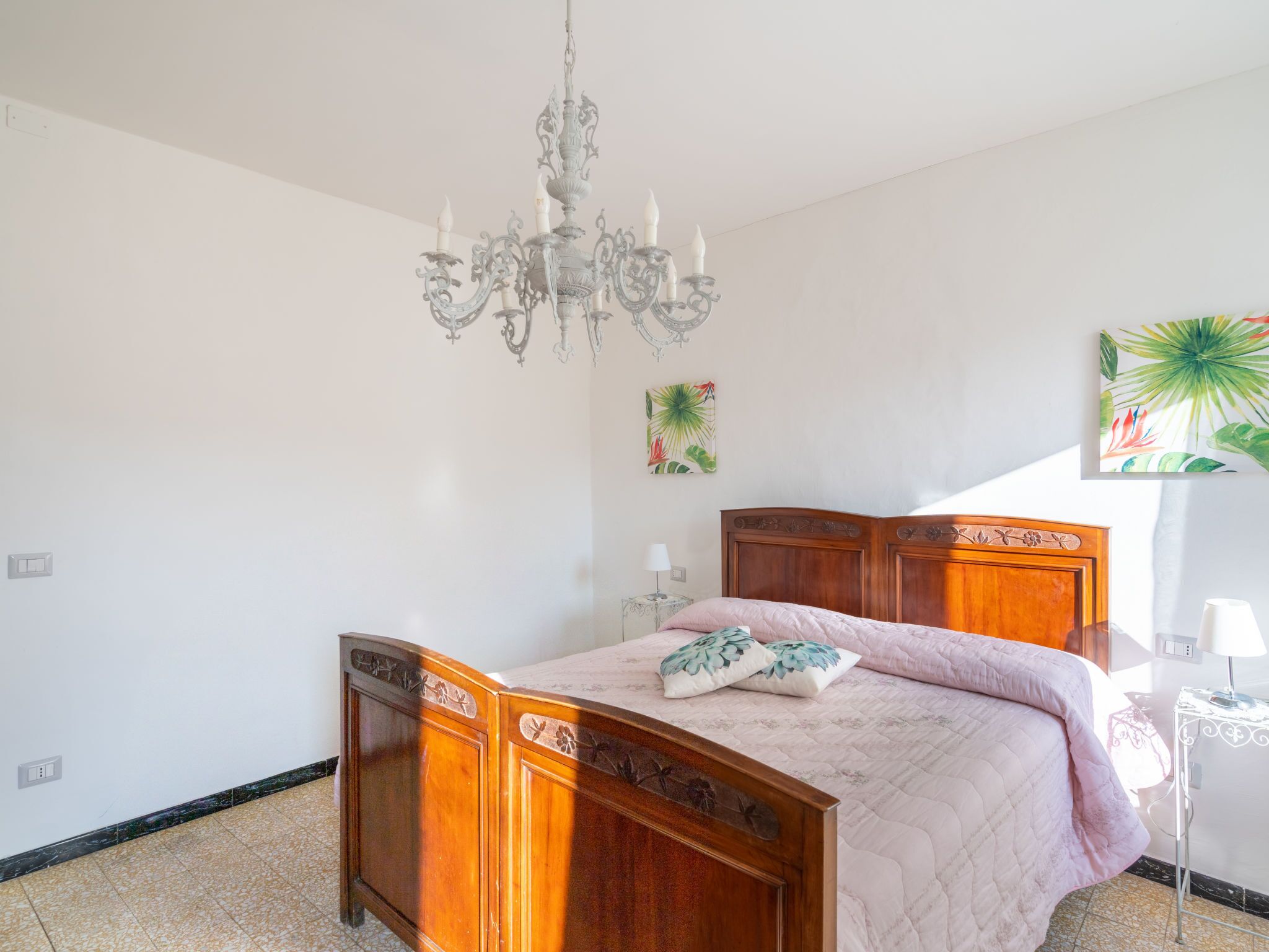 Una camera da letto con un letto di legno, un lampadario e una finestra con una pianta.