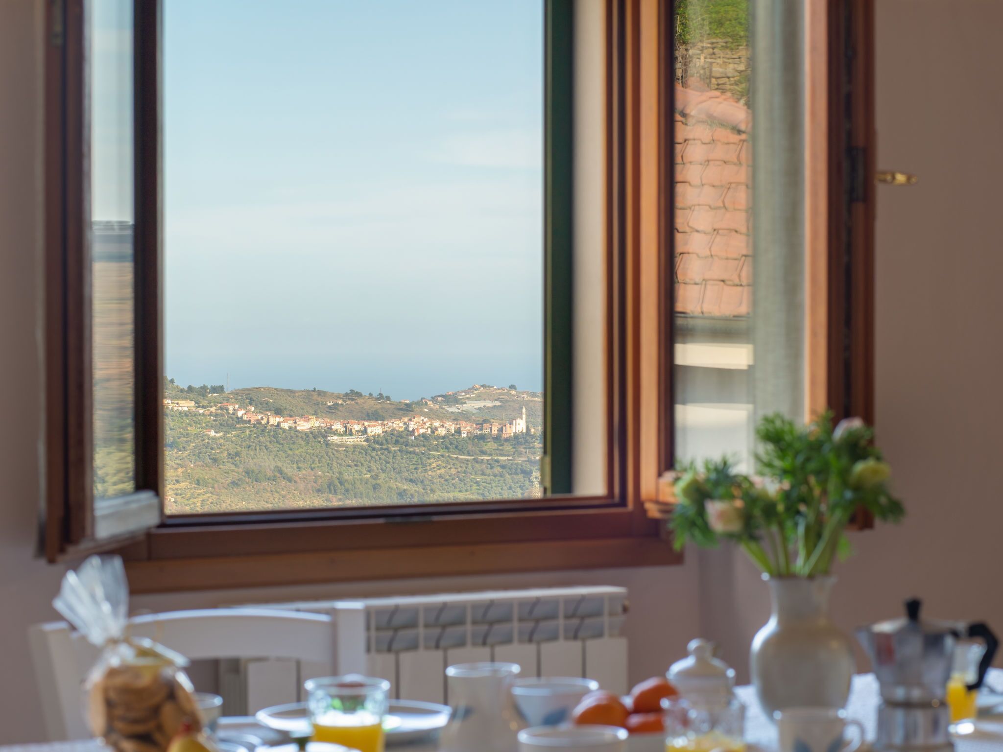 A dining table with breakfast items and a view of a coastal landscape through a window.