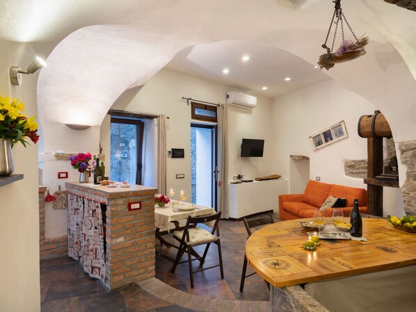 A cozy dining area with a wooden table, chairs, and a brick partition. - Mulino Rossi (PTB170) by Interhome (Pietrabruna)