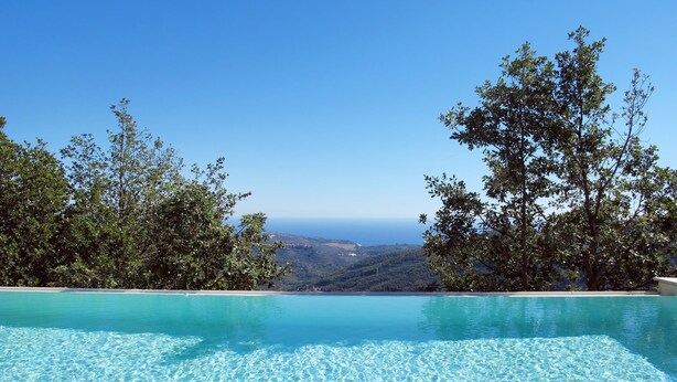 A clear blue pool with a view of the ocean and hills in the background. - Azzurra (PTB145) by Interhome (Pietrabruna)