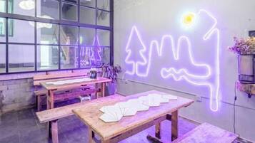 Et værelse med træbænke og borde, et neon lysdesign på væggen og et vindue med udsigt.